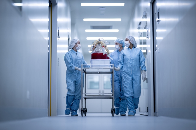 Photo of doctors in scrubs wheeling a trolley down a corridor