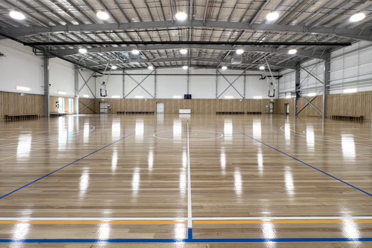 An empty basketball court with reflections from lighting on the roof.