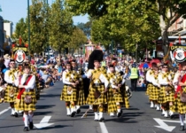 Bagpipe marching band wearing Scottish kilts playing and walking down the street