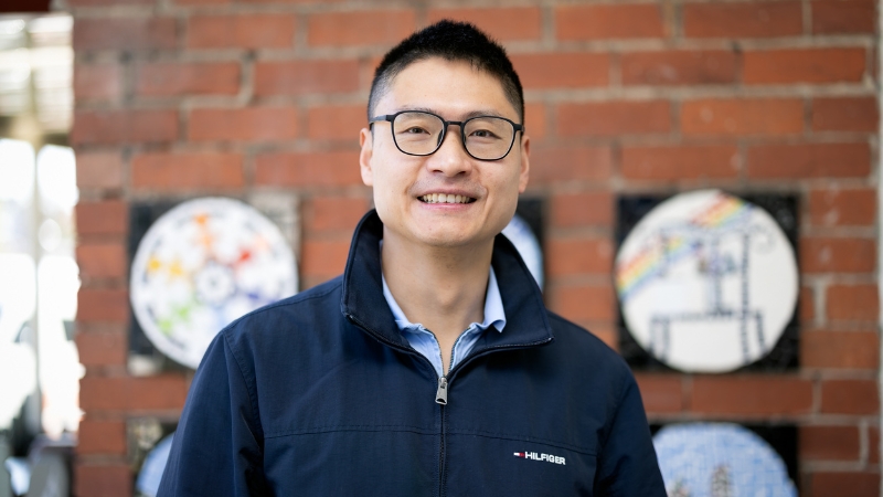 Jack Zhou smiling, wearing a blue jumper