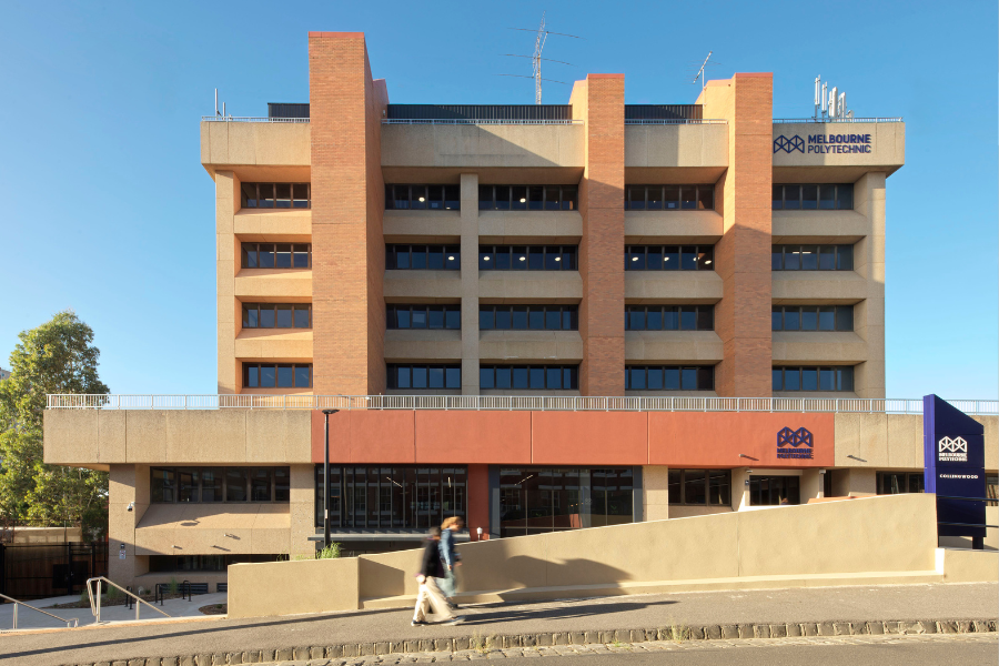 Exterior view of Collingwood Melbourne Polytechnic building, with a person walking in front.
